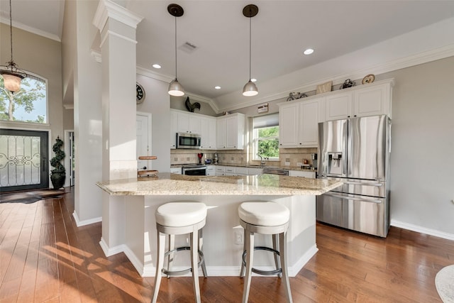 kitchen featuring ornamental molding, appliances with stainless steel finishes, dark wood-style floors, and light stone countertops