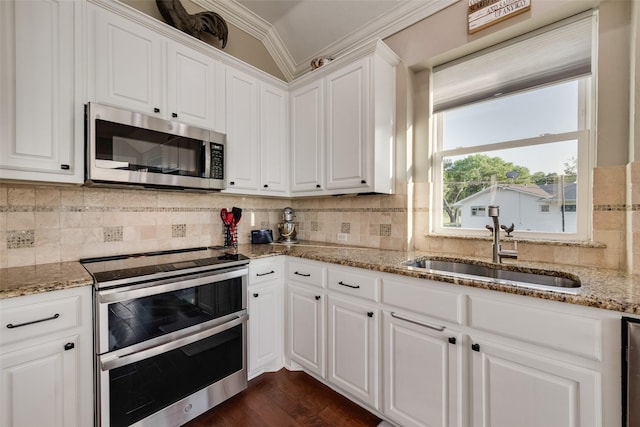 kitchen with stainless steel appliances, light stone countertops, white cabinetry, and a sink
