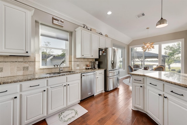 20065 Fiddlers Green Rd, Frisco, TX 75036 - kitchen featuring appliances with stainless steel finishes, white cabinets, dark wood finished floors, backsplash, and hanging light fixtures