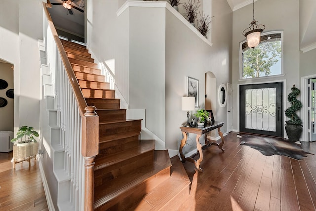 foyer entrance with stairs, hardwood / wood-style floors, and a towering ceiling
