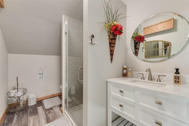 full bath featuring a shower stall, wood finished floors, vanity, toilet, and lofted ceiling