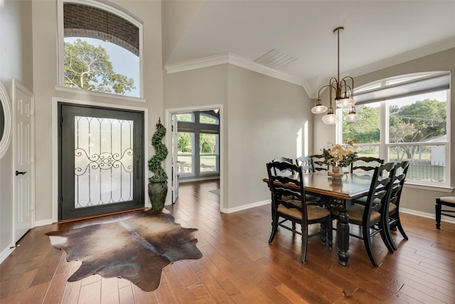dining space with crown molding, baseboards, wood-type flooring, and a chandelier
