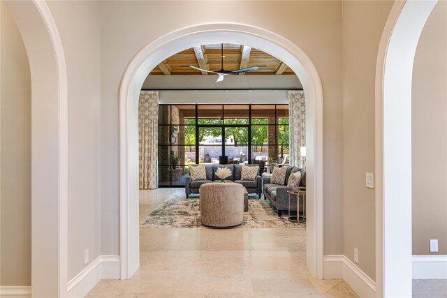 foyer featuring arched walkways, ceiling fan, and baseboards