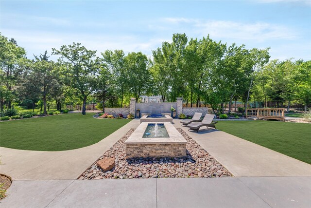 view of property's community featuring fence, a yard, and an outdoor fire pit