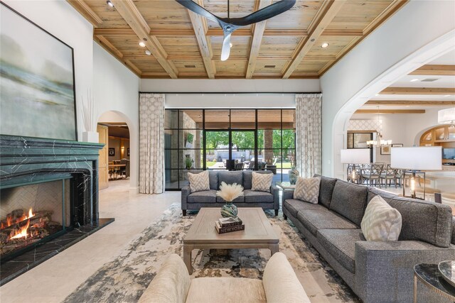 living area with arched walkways, beamed ceiling, wood ceiling, and a premium fireplace