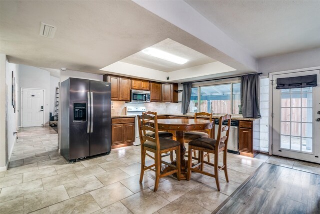 dining space with visible vents, a raised ceiling, and baseboards