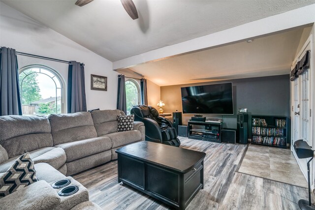 living area featuring vaulted ceiling with beams, a ceiling fan, and wood finished floors