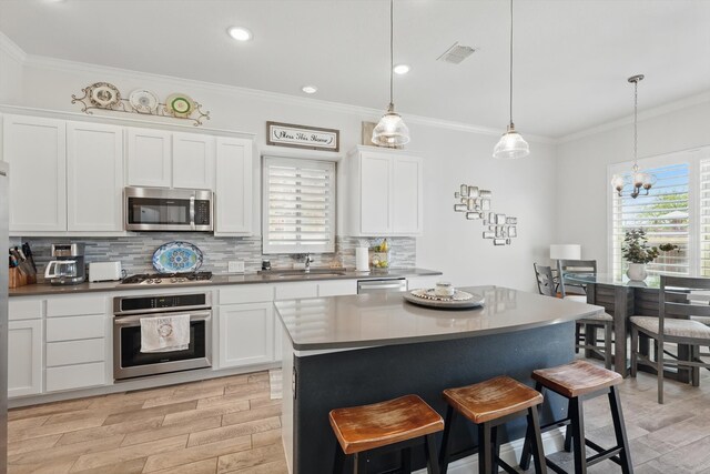 kitchen with a sink, light wood finished floors, stainless steel appliances, backsplash, and visible vents