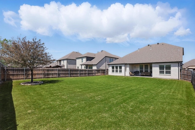rear view of house with a fenced backyard and a yard