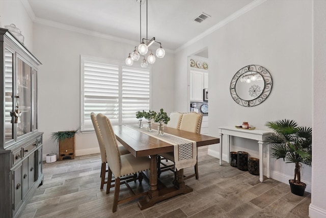 dining room with visible vents, ornamental molding, light wood-style flooring, and an inviting chandelier