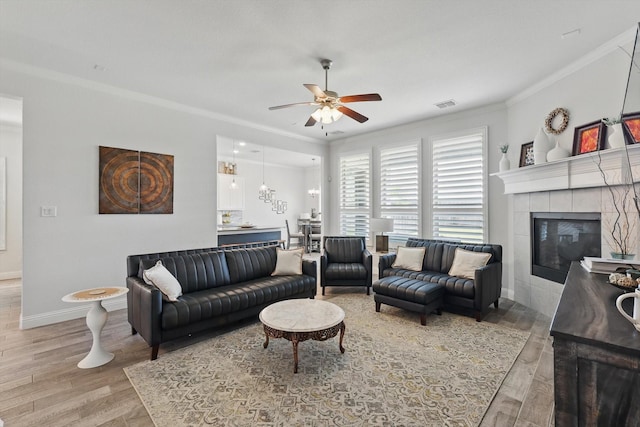 living area featuring crown molding, visible vents, wood finished floors, baseboards, and a ceiling fan