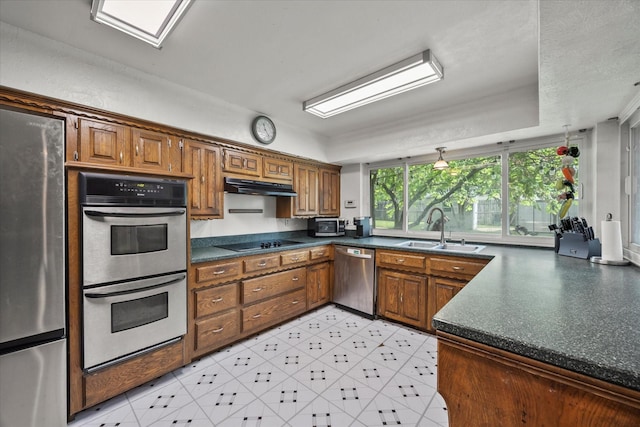 9008 Flicker Ln, Dallas, TX 75238 - kitchen with stainless steel appliances, a sink, dark countertops, under cabinet range hood, and brown cabinetry