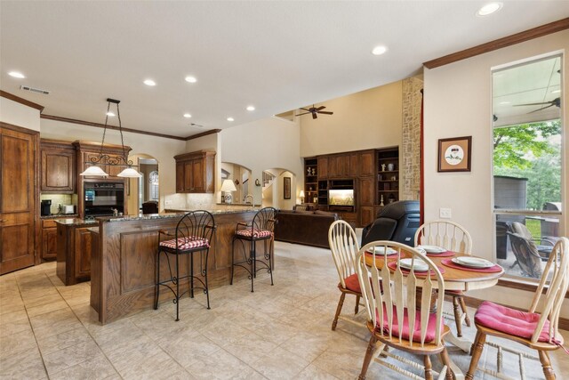 kitchen featuring a ceiling fan, arched walkways, a breakfast bar area, and ornamental molding
