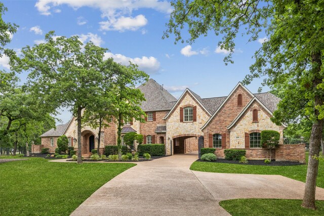 view of front facade featuring a front lawn, stone siding, and concrete driveway