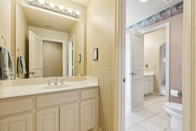 bathroom featuring tile patterned floors, wallpapered walls, and visible vents