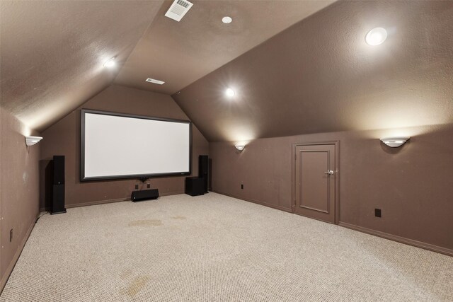 carpeted cinema with baseboards, visible vents, a textured ceiling, and lofted ceiling