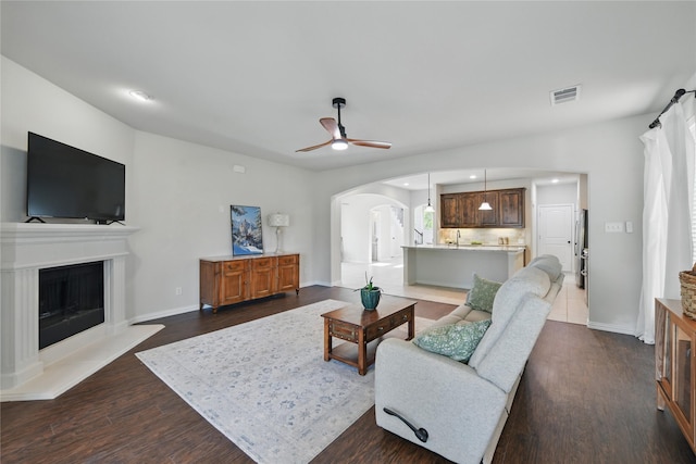 400 Sterling Rdg, Lantana, TX 76226 - living area featuring a fireplace with raised hearth, visible vents, dark wood finished floors, ceiling fan, and arched walkways