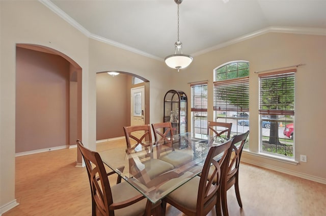 dining space with crown molding, arched walkways, baseboards, and vaulted ceiling