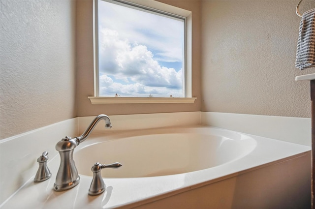 bathroom featuring a garden tub and a textured wall