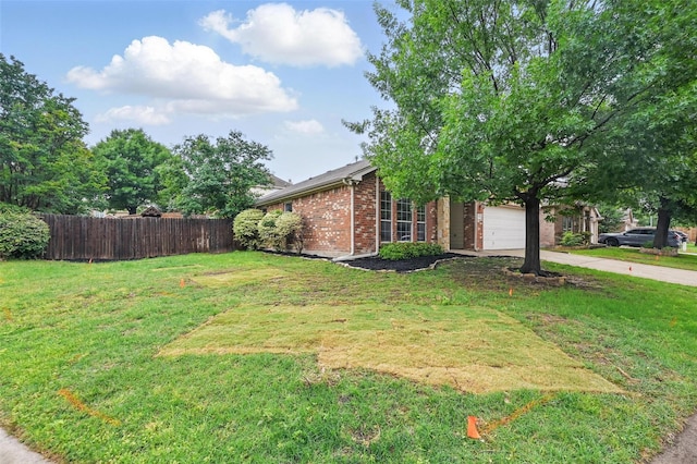 view of yard featuring fence, driveway, and a garage