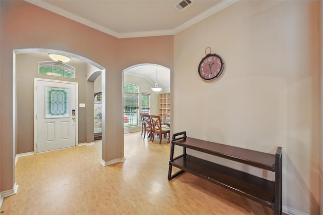 foyer entrance with arched walkways, baseboards, visible vents, and ornamental molding