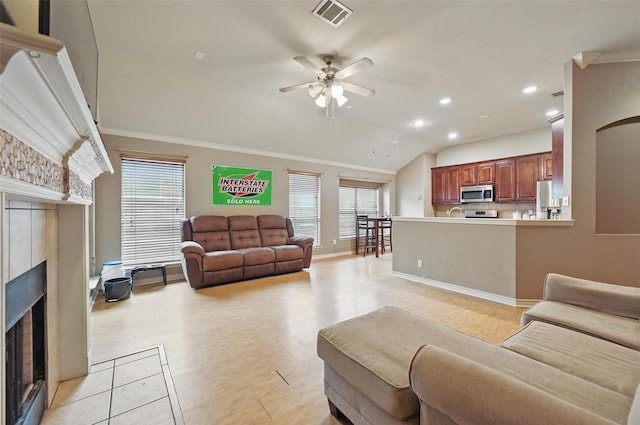 living area with a ceiling fan, visible vents, a wealth of natural light, and a fireplace