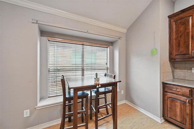dining area with crown molding, baseboards, and light wood-style floors