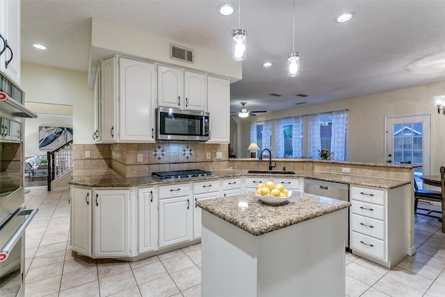 kitchen featuring visible vents, a ceiling fan, a peninsula, a sink, and appliances with stainless steel finishes