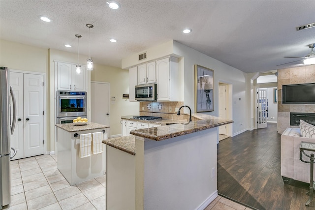 living room featuring visible vents, wood finished floors, a fireplace, baseboards, and a ceiling fan