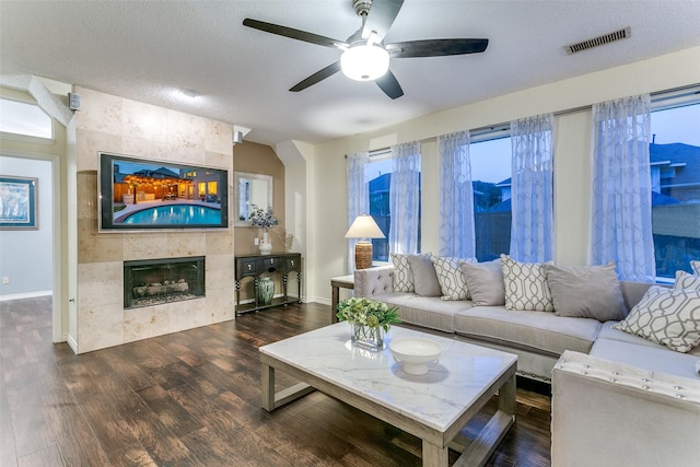 living room featuring a ceiling fan, visible vents, wood finished floors, a tile fireplace, and baseboards