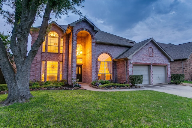 traditional-style house featuring brick siding, a front lawn, concrete driveway, an attached garage, and a shingled roof
