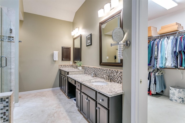 full bath featuring a walk in closet, vanity, baseboards, decorative backsplash, and a stall shower