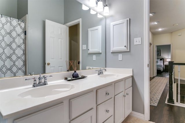 full bath featuring a sink, baseboards, and double vanity