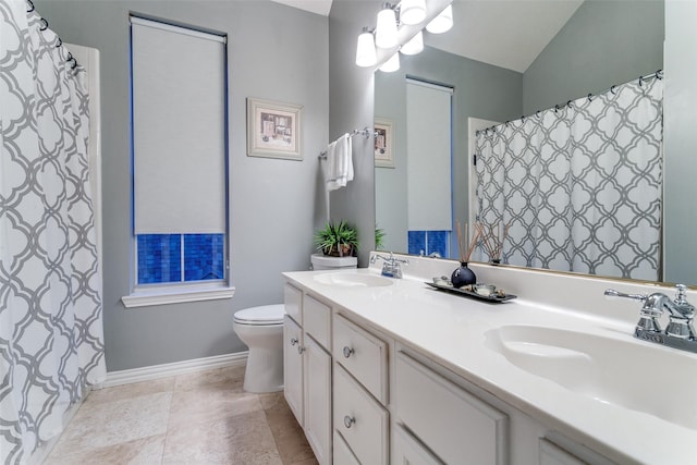 bathroom featuring double vanity, a sink, baseboards, and toilet