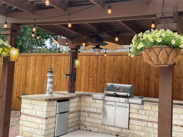 view of patio featuring fence, a ceiling fan, exterior kitchen, and area for grilling