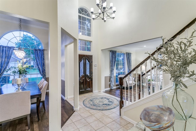 entryway with baseboards, ornamental molding, a chandelier, a high ceiling, and stairs
