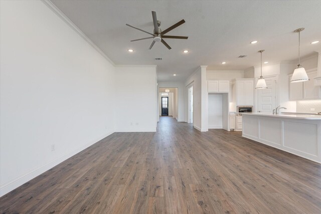 unfurnished living room featuring crown molding, a ceiling fan, dark wood finished floors, and recessed lighting