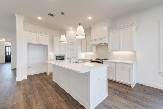 kitchen featuring a center island with sink, white cabinets, tasteful backsplash, a sink, and appliances with stainless steel finishes
