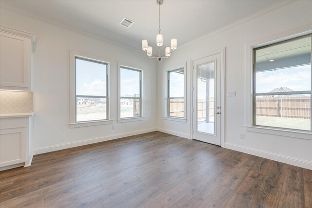 unfurnished dining area featuring an inviting chandelier, ornamental molding, dark wood-style floors, and visible vents