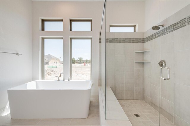 full bathroom featuring tile patterned floors, a freestanding tub, a stall shower, and a wealth of natural light