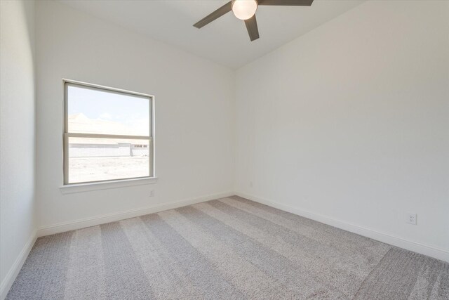 carpeted spare room featuring baseboards and ceiling fan