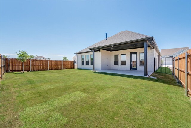 rear view of property featuring a fenced backyard, roof with shingles, brick siding, a patio area, and a lawn
