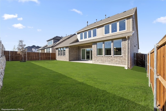rear view of house featuring brick siding, a fenced backyard, and a yard