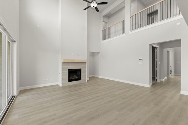 2206 Stratford Rd, Rockwall, TX 75087 - unfurnished living room with a towering ceiling, baseboards, a ceiling fan, wood finished floors, and a fireplace
