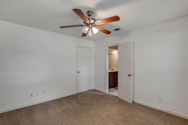 unfurnished bedroom with baseboards, ensuite bathroom, light colored carpet, and visible vents