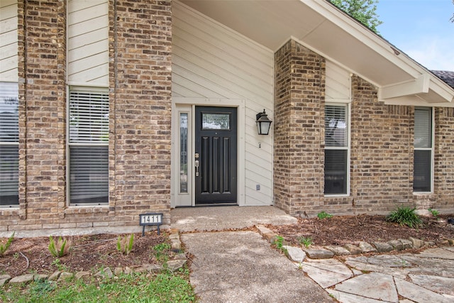 entrance to property with a porch and brick siding