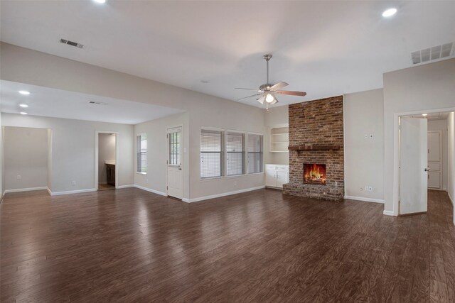 unfurnished living room with ceiling fan, dark wood-style flooring, visible vents, a brick fireplace, and baseboards