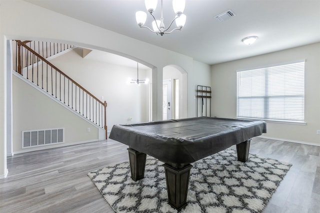 rec room with visible vents, arched walkways, light wood finished floors, and a notable chandelier