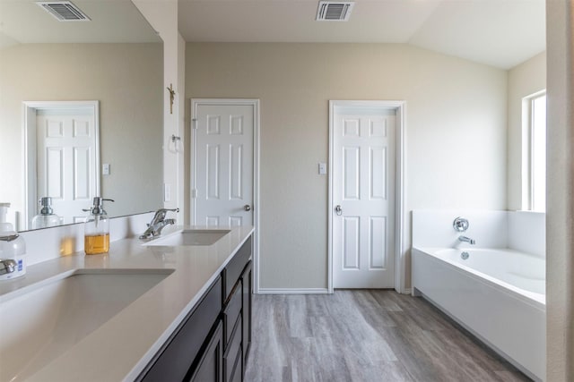 bathroom with visible vents, a sink, lofted ceiling, and wood finished floors