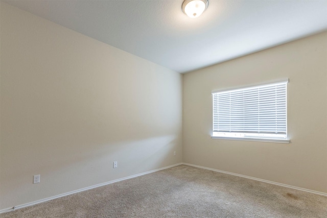 carpeted empty room featuring baseboards